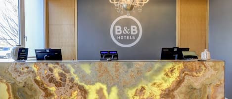 A reception desk with a marble top, a chandelier, and a B&B Hotels sign.
