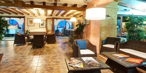 A lobby with wicker furniture, a tiled floor, and a reception desk. - Hotel La Conchiglia (Dorgali)