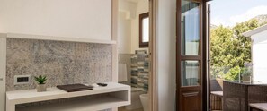 A bathroom with a marble backsplash, a small plant, and a white sink. - Hotel La Conchiglia (Dorgali)