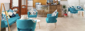 A modern hotel lobby with teal sofas and chairs, a reception desk, and a stone fireplace. - Hotel La Conchiglia (Dorgali)