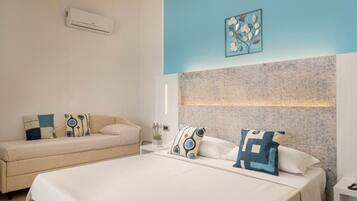 A modern bedroom with a large bed, a sofa, and a small table with a phone.