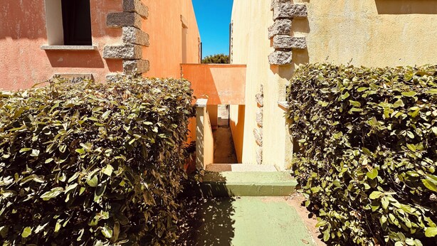 A narrow alleyway flanked by buildings with stone walls and a clear blue sky above.