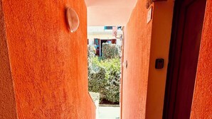A corridor with orange walls and tiled flooring leading to a door.