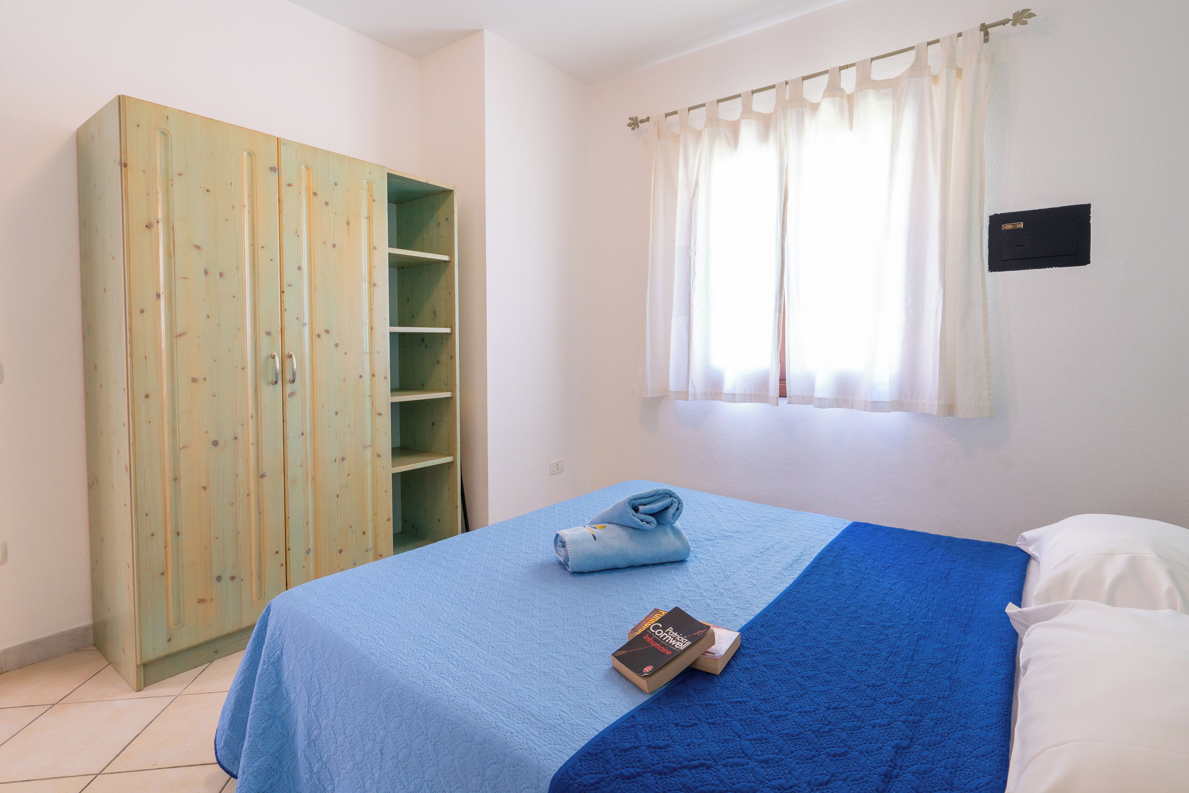 A bedroom with a bed, a wardrobe, and a window with curtains.