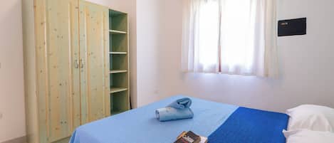 A bedroom with a bed, a wardrobe, and a window with curtains.