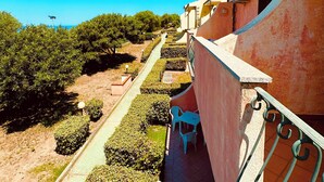 A balcony with a view of a garden and a clear blue sky.