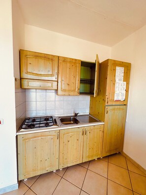 A kitchen with wooden cabinets, a gas stove, and a sink. - Le Corti del Turchese Residence (Badesi)