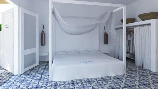 A white four-poster bed with a canopy, a wardrobe with baskets, and a tiled floor.