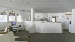 A reception area with a white reception desk, a computer, and a seating area with a chair and a table.