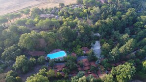 An aerial view of a residential area with a swimming pool surrounded by houses with red roofs. - Seven Hills Village (Rome)