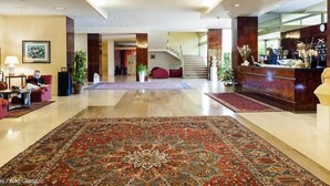 Un hall d’entrée spacieux, agrémenté d’un grand tapis décoratif, d’un comptoir de réception et d’un escalier menant aux étages supérieurs.
