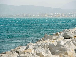 Un paysage urbain côtier avec une rive rocheuse et des bâtiments en arrière-plan.