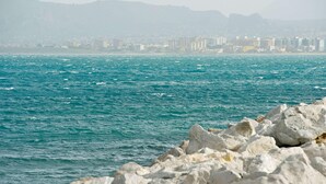 Un paysage urbain côtier avec une rive rocheuse et des bâtiments en arrière-plan.