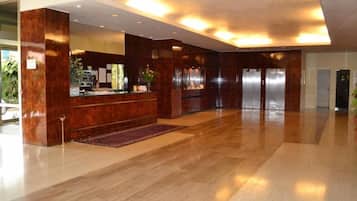 Un hall d’entrée spacieux avec un comptoir d’accueil, un grand miroir et un plancher en bois.