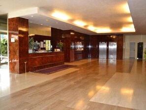 Un hall d’entrée spacieux avec un comptoir d’accueil, un grand miroir et un plancher en bois.