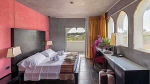 A hotel room with a bed, bedside lamps, a desk with a chair, a window with curtains, and a view of greenery outside. - Amareclub Baia Dei Turchi Resort - Adults Only (Otranto)