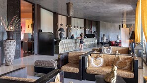 A modern lobby with patterned sofas, a reception desk, and hanging pendant lights. - Amareclub Baia Dei Turchi Resort - Adults Only (Otranto)