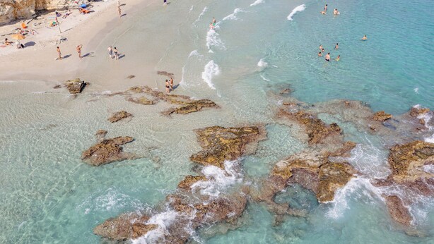A beach with clear turquoise water, rocky formations, and people enjoying the shore. - Amareclub Baia Dei Turchi Resort - Adults Only (Otranto)