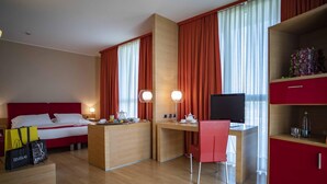 A hotel room with a bed, a desk with a computer, a chair, and a TV. - B&B Hotel Remilia (Bibbiano)