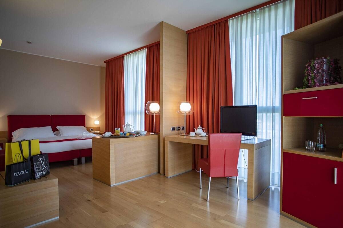 Une chambre d’hôtel avec un lit, un bureau avec un ordinateur, une chaise et un téléviseur.