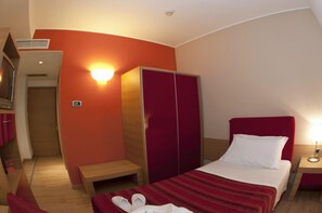 Habitació d'hotel amb llit, armari, banc i tauleta de nit.