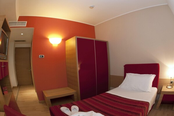 Une chambre d’hôtel avec un lit, une armoire, un banc et une table de chevet.