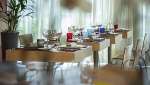 A restaurant with tables set for dining, featuring clear glassware and plates, and a potted plant in the background. - B&B Hotel Remilia (Bibbiano)