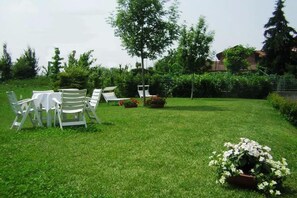 Une pelouse bien entretenue, agrémentée de meubles de jardin et d’un parterre de fleurs.