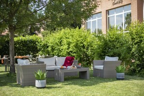 Un espace extérieur aménagé avec des meubles en osier et des plantes en pot.