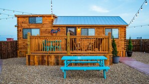 A wooden cabin with a porch, a blue bench, and string lights. - Amarillo by Morning (Amarillo)