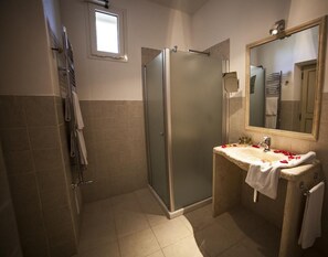 Ein Badezimmer mit einer Duschkabine, einem Waschbecken mit Rosenblüten und einem Spiegel.