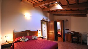 A bedroom with a wooden ceiling, a bed with a red bedspread, a nightstand with a lamp, and a wooden wardrobe. - Il Podere del Germano Reale (Coriano)