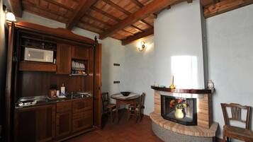 A kitchen with wooden cabinets, a microwave, a dining table with chairs, and a fireplace.