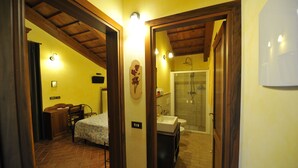 A bedroom with a bed, a desk, and a chair. There is a bathroom with a sink, toilet, and shower. - Il Podere del Germano Reale (Coriano)