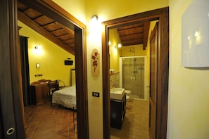 A bedroom with a bed, a desk, and a chair. There is a bathroom with a sink, toilet, and shower. - Il Podere del Germano Reale (Coriano)
