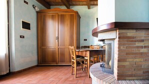 A dining area with a wooden table and chairs, a large wooden cabinet, and a brick fireplace. - Il Podere del Germano Reale (Coriano)