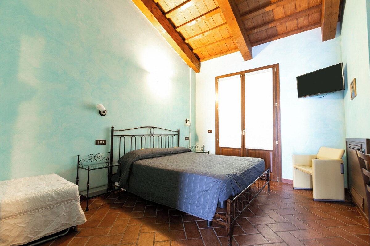 A bedroom with a bed, a chair, a television, and a door.