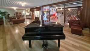 A spacious lobby with a grand piano, wooden flooring, and a reception area. - Excelsior Hotel Cimone Lowcost (Primiero San Martino di Castrozza)