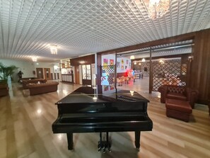 A spacious lobby with a grand piano, wooden flooring, and a reception area. - Excelsior Hotel Cimone Lowcost (Primiero San Martino di Castrozza)