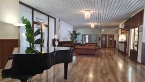 Un lobby amplio con un piano de cola, asientos cómodos y un techo con diseño.
