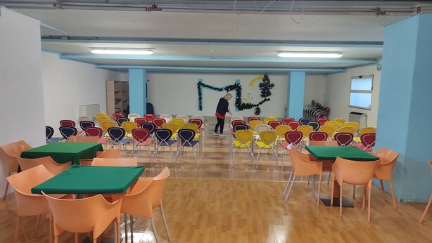 A conference room with rows of chairs and tables, a person cleaning, and a Christmas tree decoration. - Excelsior Hotel Cimone Lowcost (Primiero San Martino di Castrozza)