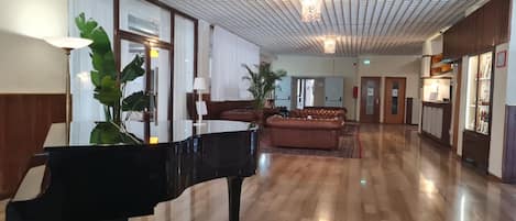 Un lobby amplio con un piano de cola, asientos cómodos y un techo con diseño.