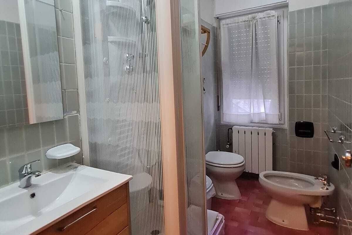 Ein Badezimmer mit Duschkabine, Toilette, Bidet, Waschbecken und Spiegel.
