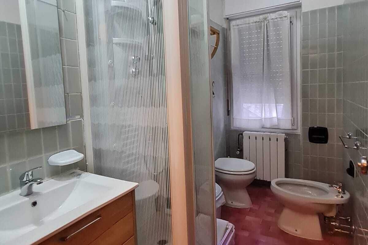 A bathroom with a shower enclosure, a toilet, a bidet, a sink, and a mirror.