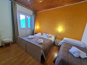 Een hotelkamer met twee bedden, een klein tafeltje, een stoel en een raam met gordijnen.