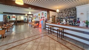 Un vestíbulo amplio con una zona de bar, arreglos de asientos y un techo estampado.
