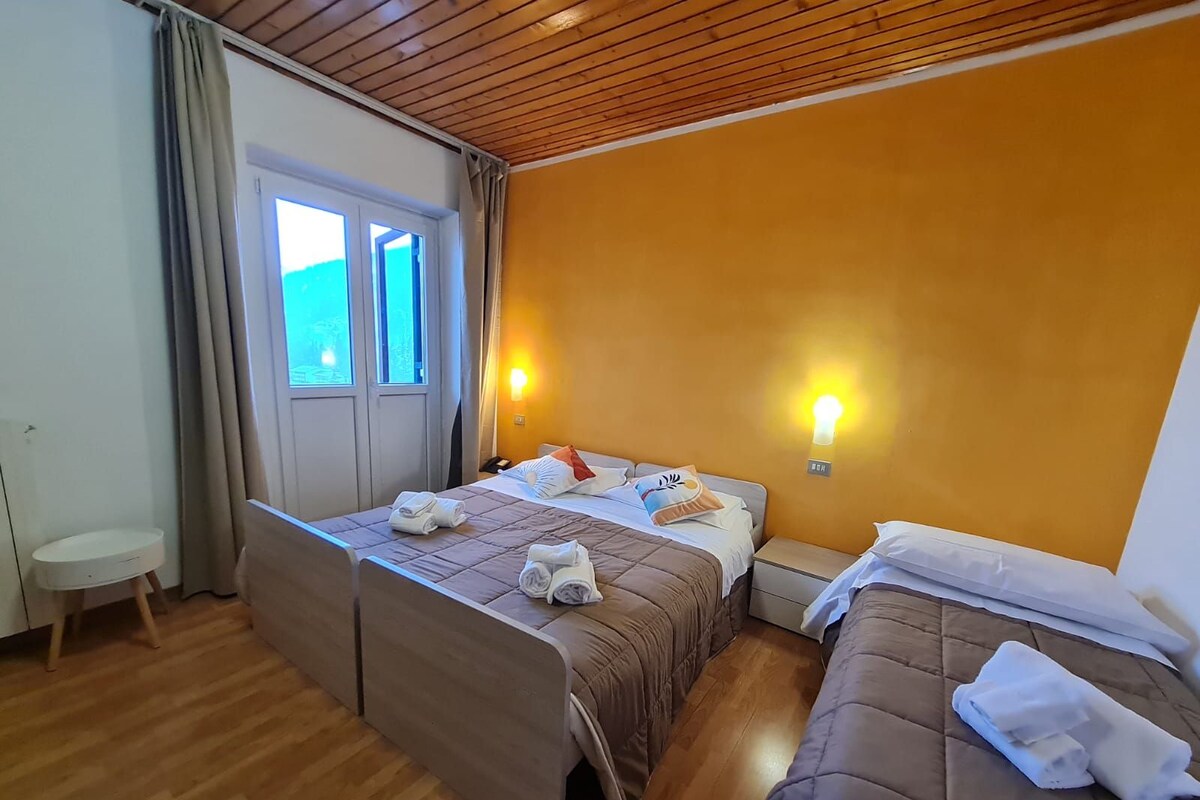 Une chambre d’hôtel avec deux lits, une petite table, une chaise et une fenêtre avec des rideaux.