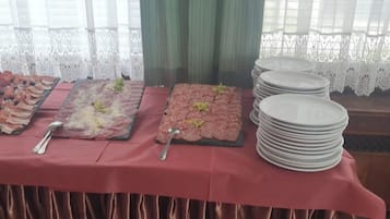 Un tavolo da buffet con diversi cibi e piatti impilati.