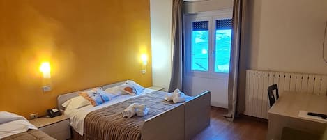 A hotel room with a wooden ceiling, a bed with a headboard, a sofa, a small table, and a window with curtains.