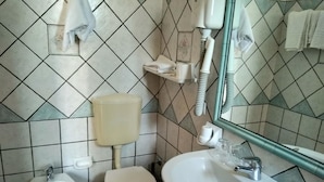A bathroom with a toilet, bidet, sink, and mirror. - Tramonto D'oro Terme (Forio)